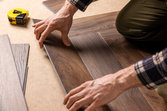 worker installing new vinyl tile wood texture flooring in a herringbone pattern. home improvement