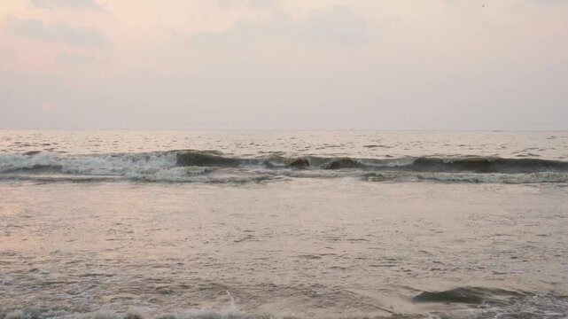 Gentle ocean waves crashing on Marina Beach in Chennai at sunrise