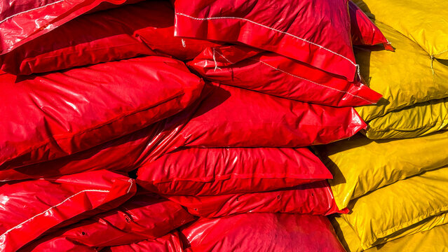 Close-up of stacked red and yellow plastic sacks in bright daylight at a warehouse, vivid textures and contrast, suitable for industrial editorial, packaging design, marketing