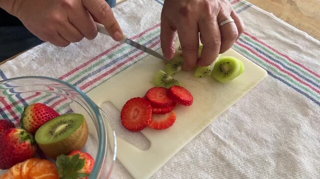 Hombre cortando kiwi y fresas en trozos peque&ntilde;os