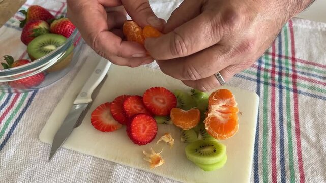 Hombre separando gajos de mandarina junto a otras frutas