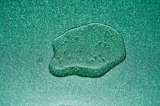 Liquid droplet on sparkling green surface creating texture