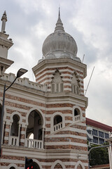 Obraz premium detail of a historic Moorish-style building in Kuala Lumpur featuring a dome, arched windows, and decorative red brick and white plaster stripes. Heritage Conservation