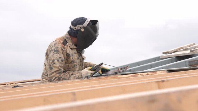 Welder Working on Rooftop Welding Metal Structures at Construction Site