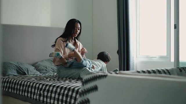 Mother and son playfully tickling and jumping on the bed in the morning