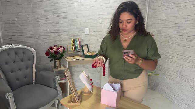 Small business owner packing handmade jewelry to ship to a customer from her home office