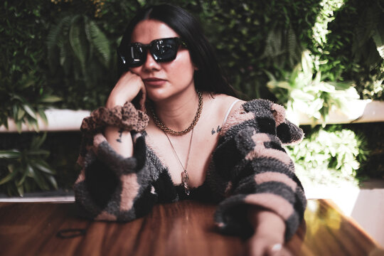 Young woman with black hair smiling. mujer sentada tomando y desayunando. mujer en jardin feliz. estilo de vida mujer feliz
