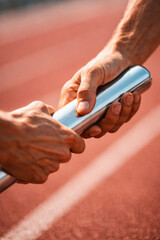 Fototapeta premium Hands exchanging a relay baton on a running track