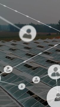 Overlaying faint user icons and glowing links spreading over glass roofs on farmland, tree line