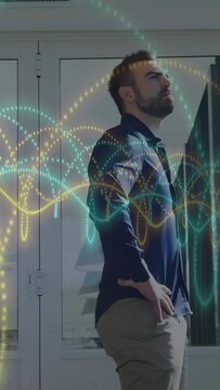 Vertical video: Man hands akimbo tilting chin by doors waveforms sweeping over face for tech demo