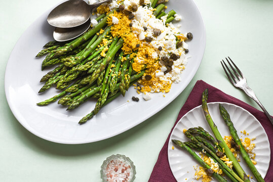 Asparagus salad Mimosa. Spring and Easter salad with grated egg, capers and aromatic dressing. Sunlight background. Healthy vegetarian balanced recipes for spring, seasonal cuisine 
