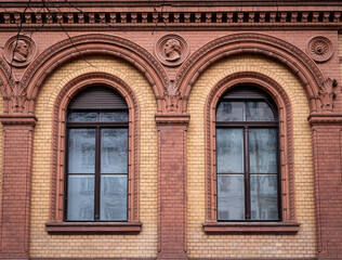 Obraz premium Architectural detail with two arched windows and decorative reliefs on a historic brick facade