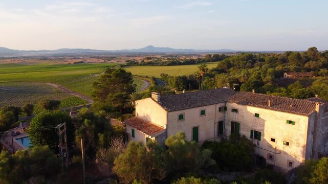Aerial view of a traditional Mediterranean house with a pool situated on a hill, at sunset in the summer