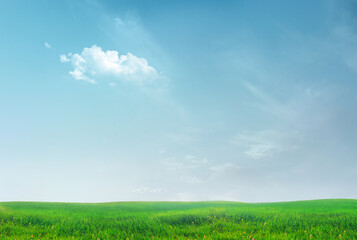 Fototapeta premium Peaceful Green Meadow Under Blue Sky With Single White Cloud Over Rolling Landscape