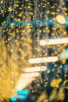 festive blurred lights with green leaves, golden holiday glow defocused through foliage background, christmas or new year eve garland bokeh