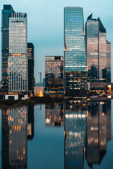 big city skyline at sunset with mirrored water reflection, modern high-rise skyscrapers at golden hour urban dusk, downtown mirroring on swimming pool, Bangkok Thailand © goami