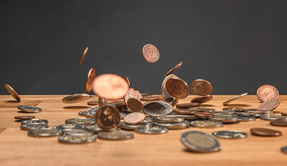 Coins falling and bouncing on wooden table motion freeze.