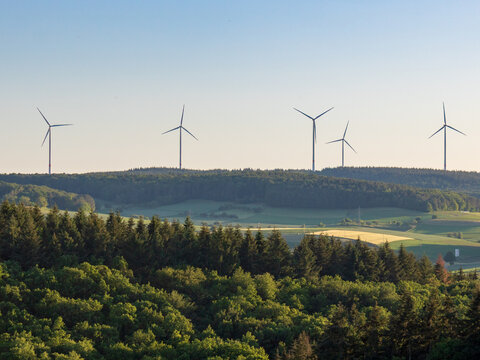 Wind turbines on horizon above forest and fields, renewable energy in Germany