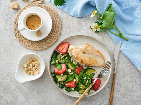 Healthy lunch with grilled chicken, salad, and coffee served on a table with decorative items and fresh greens