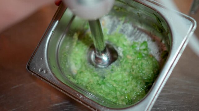 A chef in a restaurant prepares basil sauce