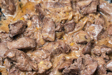 Fototapeta premium Fried chicken liver with onions in a frying pan close-up homemade food meat dish sauce