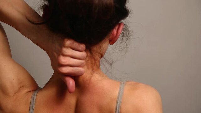 Health sport body woman doing massage with hands her neck, head, upper back. Fit naked muscles model in bra isolated in studio light with copy space. Back view closeup	
