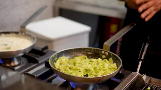 A chef in an Italian restaurant prepares pasta in a large pan