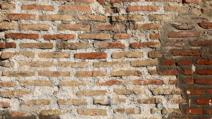 Ancient brick wall texture showing weathered orange bricks and grey mortar, indicating historic architecture, old construction, and a decaying urban background for designs © Newleks