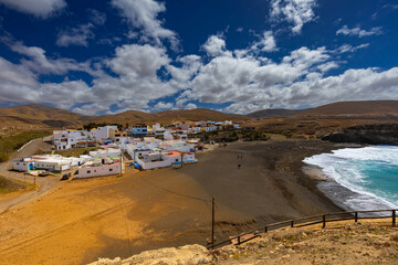 A panoramic view of the town of Ajuy in Fuerteventura, nestled on a black sand beach on the Atlantic Ocean. A background or wallpaper for your project © anettastar