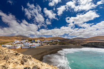 A panoramic view of the town of Ajuy in Fuerteventura, nestled on a black sand beach on the Atlantic Ocean. A background or wallpaper for your project © anettastar