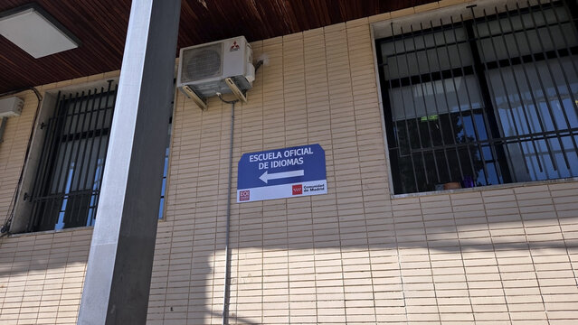 MADRID, SPAIN - FEBRUARY, 17, 2026. Official language school sign on brick facade in madrid pointing to escuela oficial de idiomas Jesus Maestro for education banner and local directory background