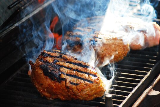 Close-up of seasoned steaks being grilled on a barbecue
