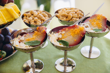 Gourmet poached pears with almond flakes and mint leaf, presenting a sweet and refreshing dessert option for a buffet © anatoliycherkas