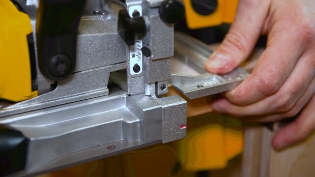 Wood lamella router in action cutting into a wooden surface. The spinning bit carves a precise groove as the attachment cutting into the material.