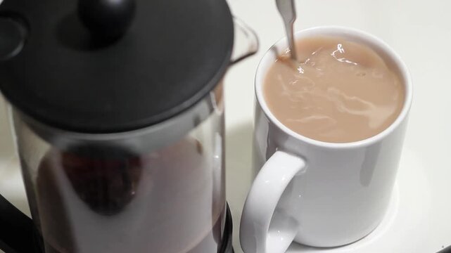 Adding sugar to milky cup of coffee. Mug in focus. HD video. 