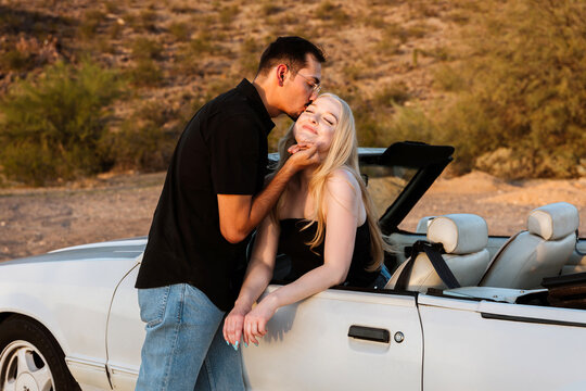 Couple showing affection in convertible in desert in classic car