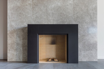 Naklejka premium A fireplace is placed in a minimalist living room with a stone wall. The space is bright with natural light. The design is simple and clean. A few logs rest inside the fireplace