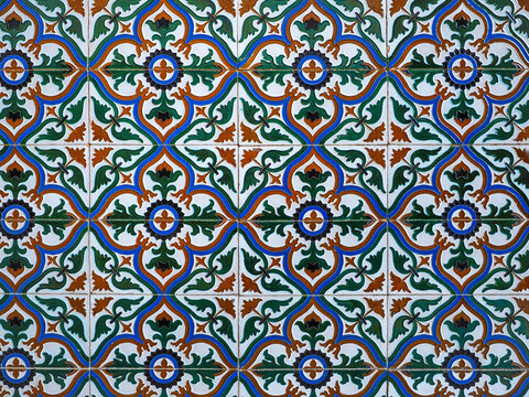 Fragment of building wall with glazed ceramic tiles, embossed vintage Mudejar, close up. Traditional ornate Spanish architecture. Abstract background, textured ornate pattern for design or backdrop.