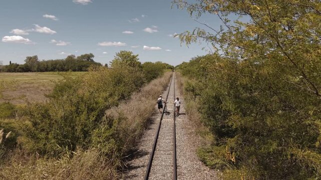 Drone Following Couple Walking Along Railway Tracks with Bicycles