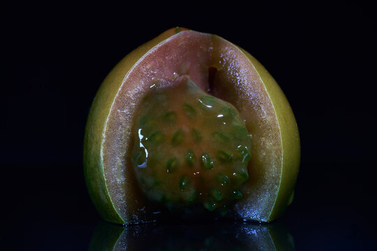 Choco tomato cut open on black background showing pulp and locules in detail