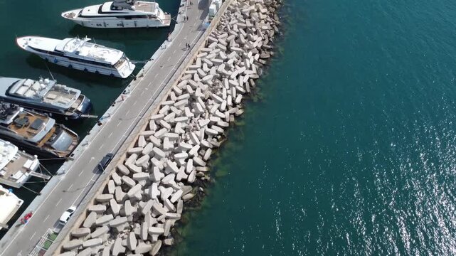 Aerial coastal breakwater with luxury yachts and calm harbor waters
