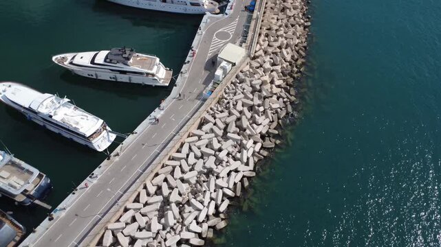 Aerial rotating view of marina breakwater and luxury yachts