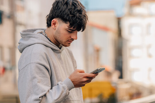 portrait of a young man with a mobile phone on the street