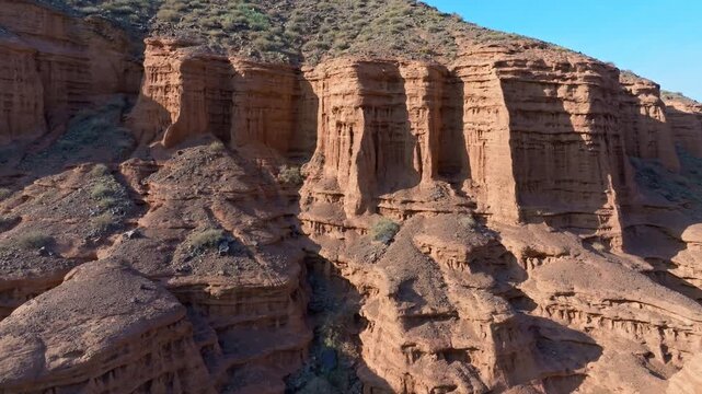 Aerial view of rugged geological formations in Kyrgyzstan. Shadows cast by unique rock layers create a serene and awe-inspiring atmosphere.