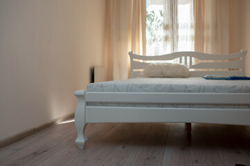 Modern bedroom with well-lit cozy atmosphere. Bed and mattress, orthopedic mattress in bedroom and pillows in white color, close-up. Interior concept of a comfortable room for sleeping.