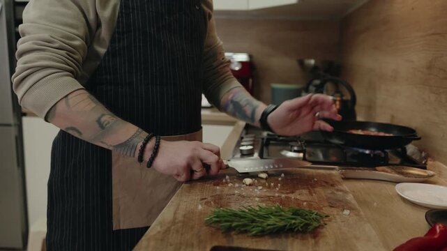 Professional Chef's Tattooed Hands Expertly Chop Fresh Ingredients on a Wooden Board in a Modern Kitchen