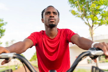 Obraz premium Young man sitting on bicycle and looking away in park, thoughtful urban lifestyle concept
