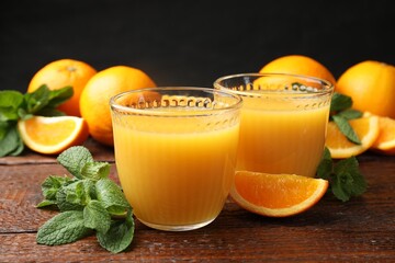 Citrus juice in glasses, fresh oranges and mint leaves on wooden table, closeup © New Africa