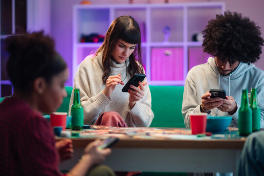 Friends phubbing during a social gathering while distracted on smartphones and digital devices