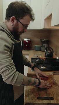 Man Prepares Raw Meat Steaks on a Wooden Cutting Board in a Modern Home Kitchen